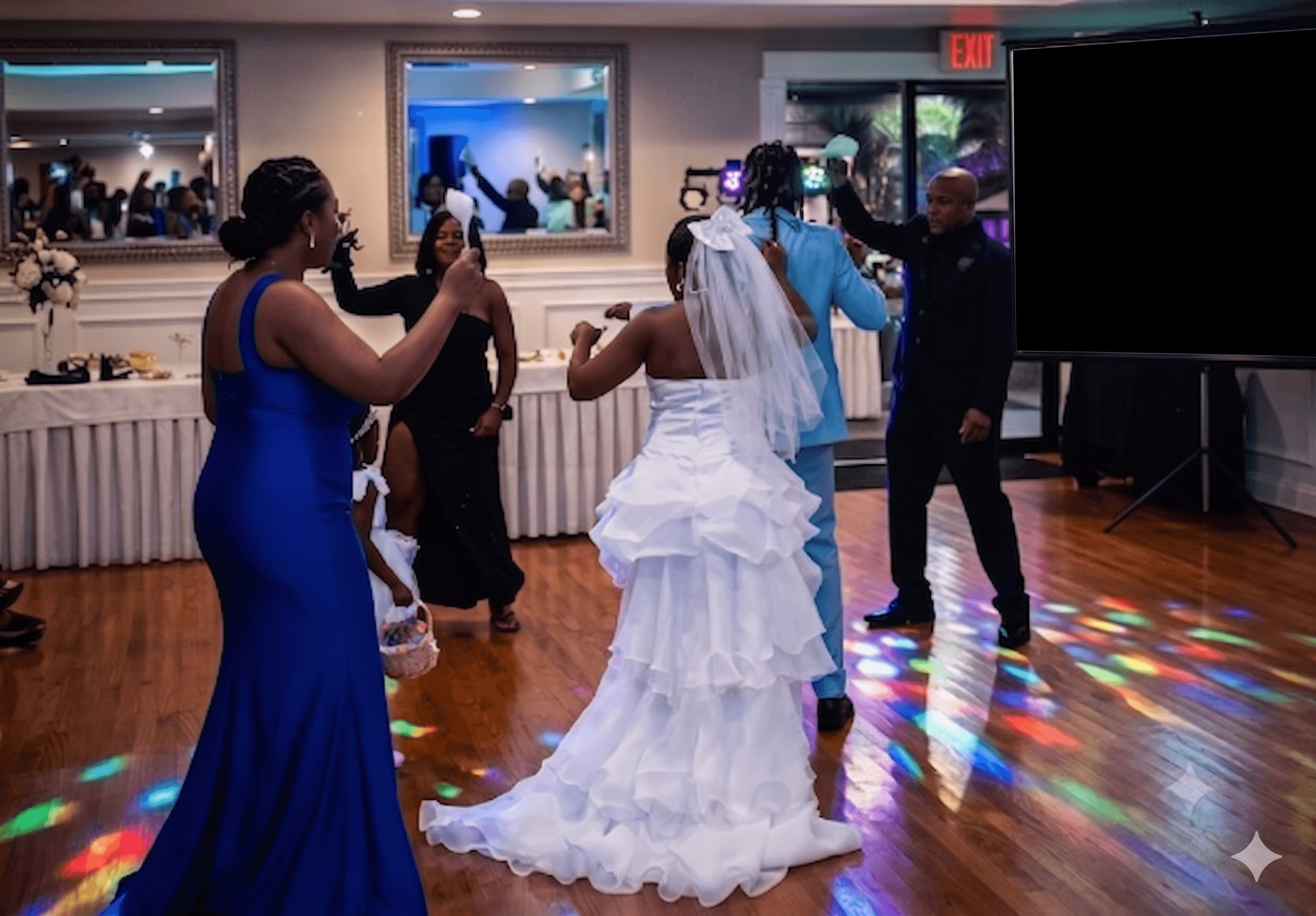 Bride and groom dance with guests on a wooden floor under colorful disco lights.